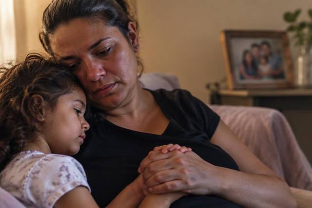 Mãe e filha abraçadas em casa após a perda de um familiar