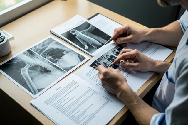 Exames de imagem, laudos e documentos organizados sobre a mesa