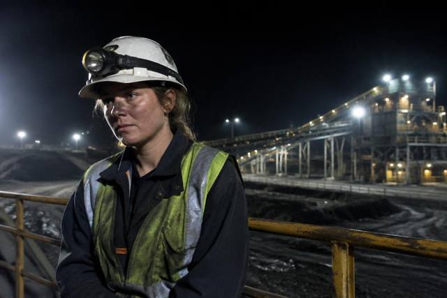 Trabalhadora da mineração cansada durante o turno da noite sob os refletores da planta